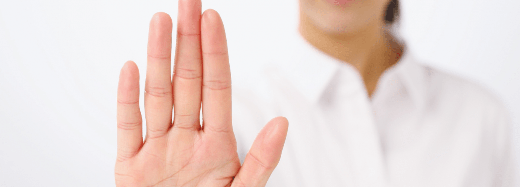 Open hand held up toward camera by person partially visible in background.