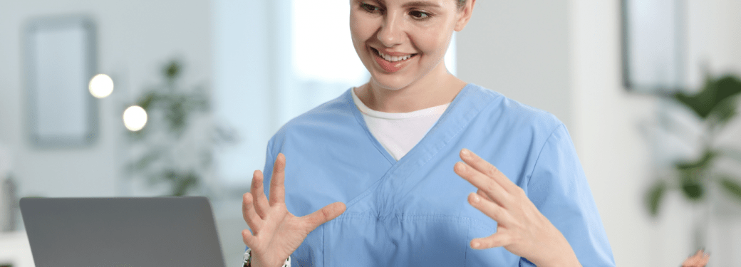 A healthcare worker interacting with another person virtually on their laptop.