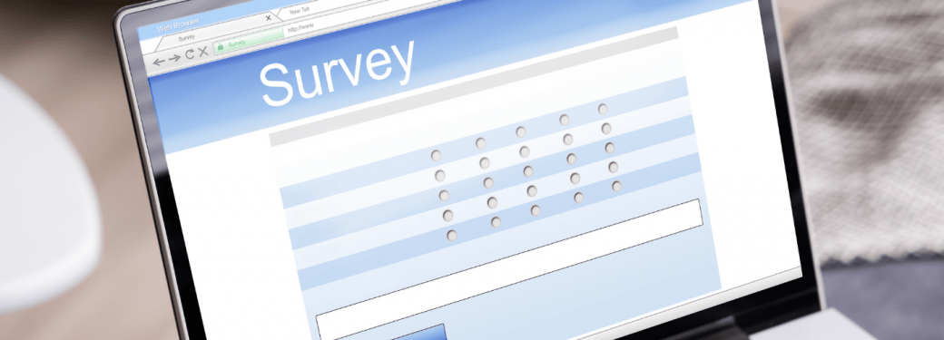 A person typing on keyboard with an online survey on their laptop screen.