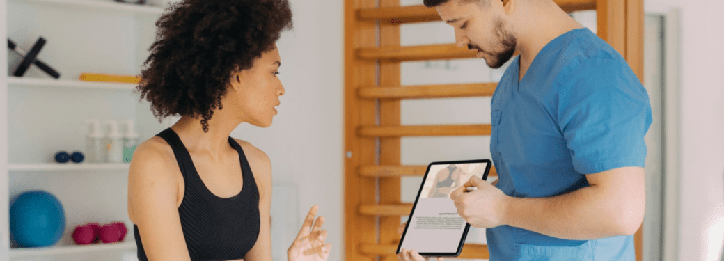 A Massage Therapist discussing treatment plan on a tablet with their patient.